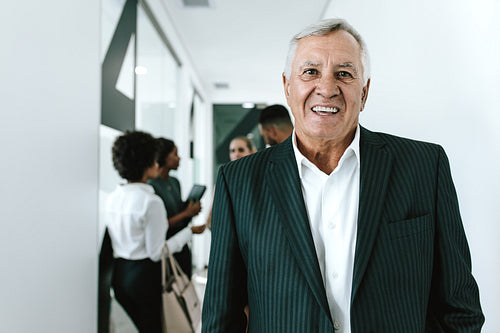 Happy senior businessman in office corridor