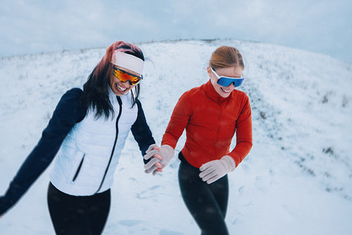 Female athletes support each other during a winter run in snow