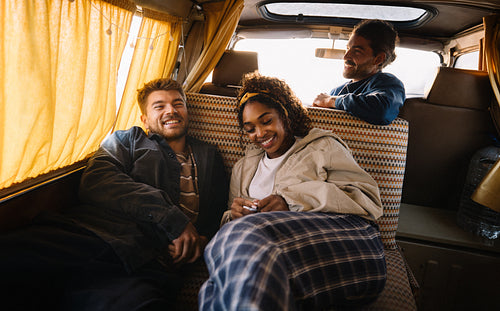 Friends relax in the back of a van enjoying a cozy travel moment together
