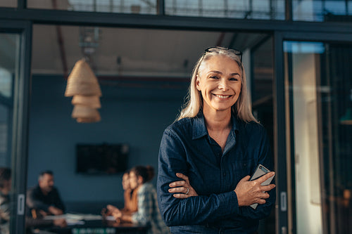 Smiling senior woman standing in office doorway