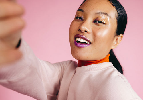 Radiant Beauty: Young Asian woman taking a selfie in a studio