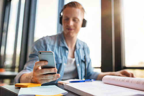 Male student using mobile phone in a library