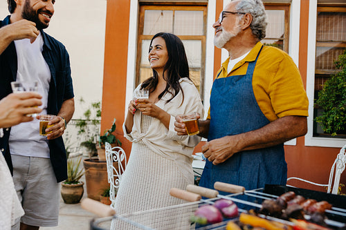 Family barbecue gathering outdoors with multi-generational members sharing food and drinks
