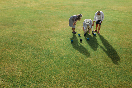 Senior persons checking the distance between boules for the result