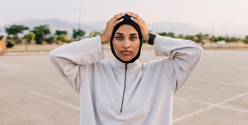 Muslim sportswoman looking at the camera with her hands on her head