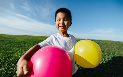 Happy boy with colorful balloons in park