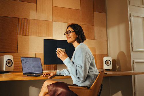 Woman works at desk with coffee and laptop in office