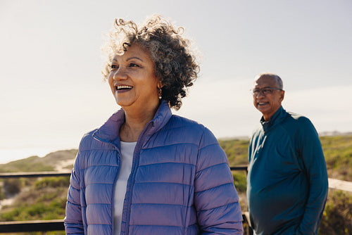 Happy senior woman standing on a foot bridge with her husband