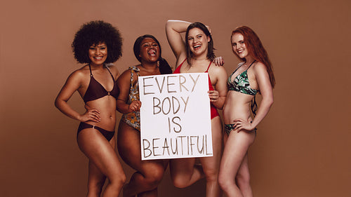 Different size females holding a every body is beautiful placard