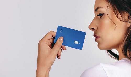 Woman embraces electronic banking as she holds a credit card close to her face in a studio
