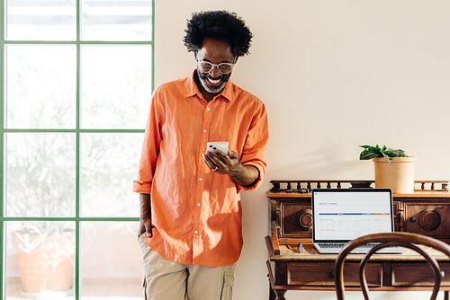 Cheerful mature man using his smartphone in his home office