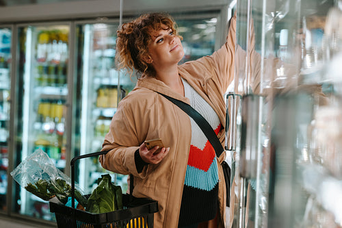 Shopper reaching product from freezer at supermarket