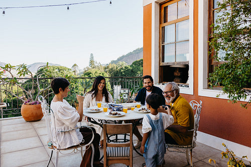 Family enjoying a meal together on a sunny veranda