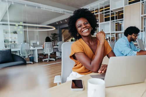 Happy business woman smiling in office boardroom with a laptop
