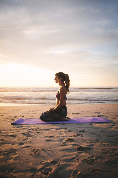 Woman doing Vajrasana pose at beach