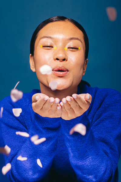 Celebrating beauty: Woman with makeup blows confetti in a studio
