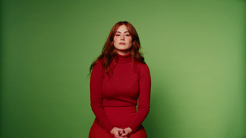 Redhead woman smiling against a green screen background in studio