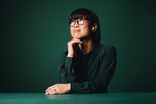 Woman with earbuds pensive in monochromatic studio portrait