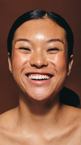 Flaunting happiness and radiance, woman with flawless skin smiles at the camera in a studio