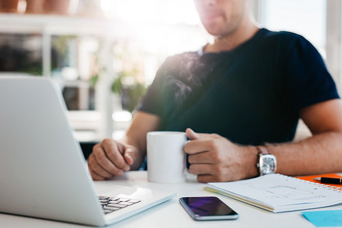 Business man sitting at his desk holding a cup of coffee
