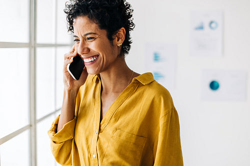 Business woman takes a phone call in an office. Professional woman smiling while talking to clients on the phone