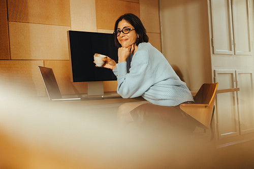 Woman pauses from work with coffee at her desk in the office