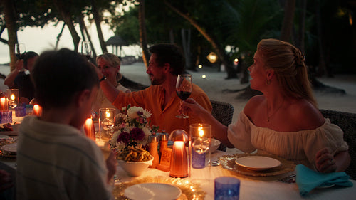 Family and friends raise a toast at a beautiful beach dinner during vacation