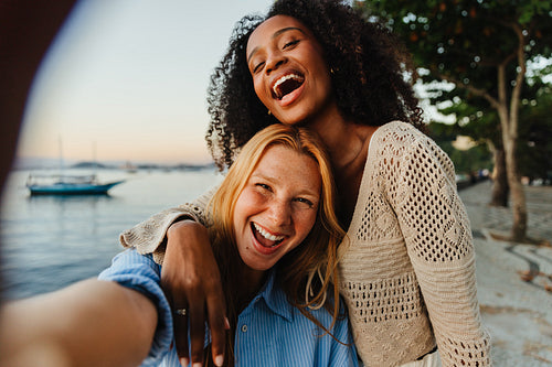 Joyful Brazilian girls laughing near a serene beach at sunset