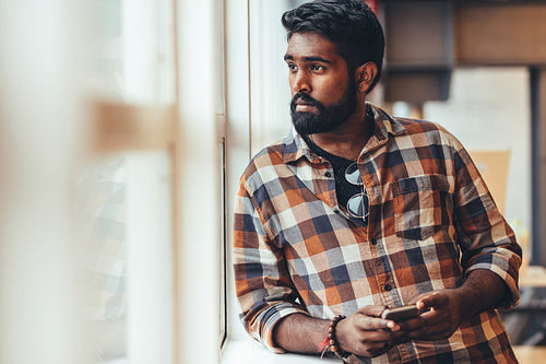 Man standing near a window looking outside
