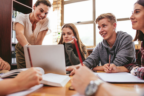 Female teacher working with college students in library