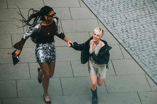 Carefree day out: friends running and laughing on a city street