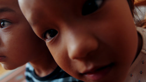 Adorable faces in the camera: Two happy little siblings play in their parents' room