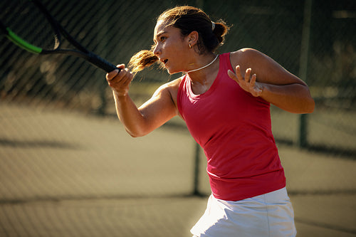 Powerful forehand action of woman playing tennis in vibrant sunlight