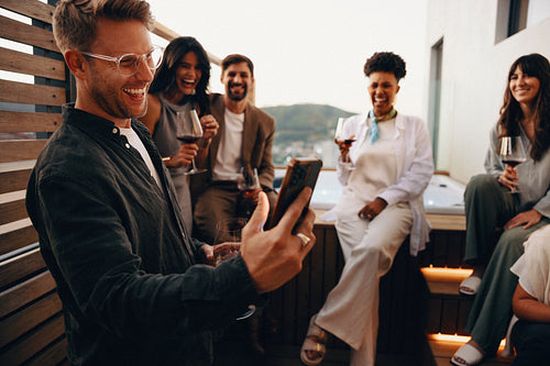 Friends enjoying drinks and laughter at a rooftop evening gathering