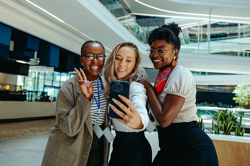 Group of young female recruits taking a selfie and celebrating a new job with bright smiles