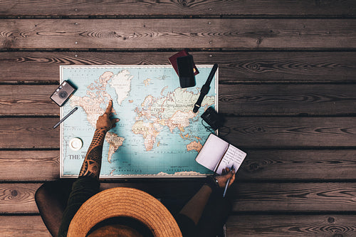 Woman planning vacation using a world map.