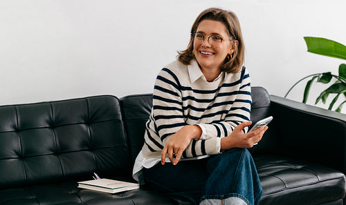 Woman working from home on couch with smartphone in a casual living room