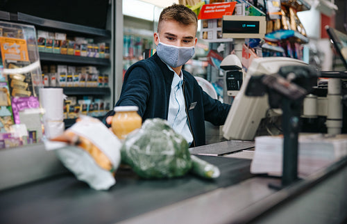 Supermarket checkout employee with face mask