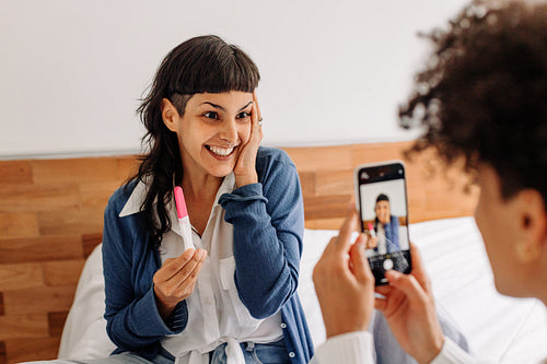 Young woman posing for a picture holding her pregnancy test