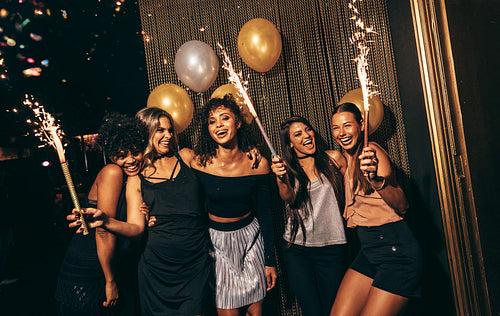 Group of women celebrating with fireworks at pub