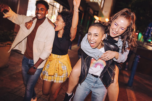 High-spirited young woman piggybacking her friend at night