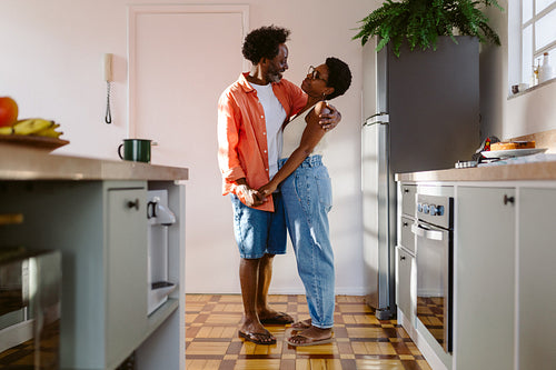 Mature couple sharing a romantic moment in their kitchen, holding hands and smiling at each other