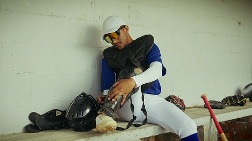 Catcher prepares for game in baseball dugout