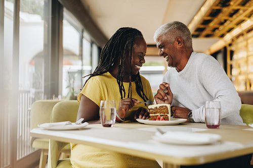 Happy mature couple sharing a delicious cake in a cafe