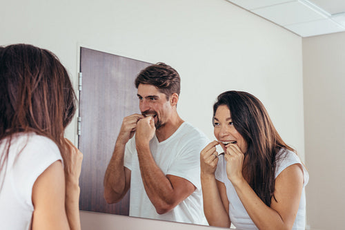 Couple using dental floss to clean their teeth