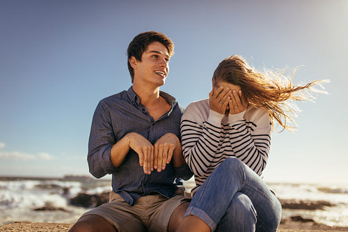 Happy couple enjoying leisure and having fun sitting on a sea wall