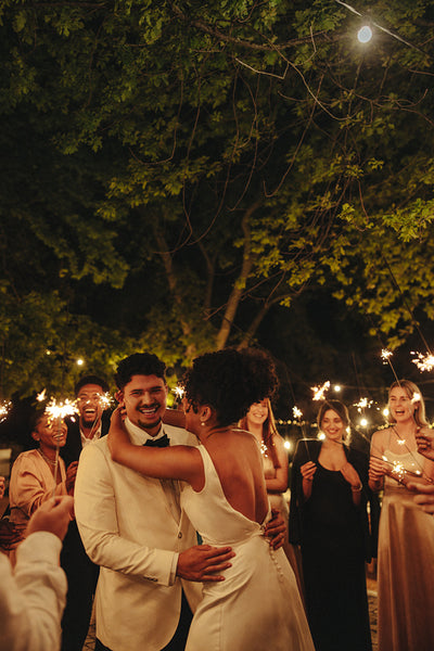 Bride and groom share a joyful first dance at an evening garden reception