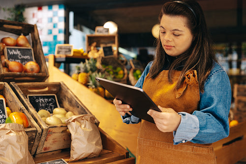 Storekeeper with Down syndrome using a digital tablet in a shop