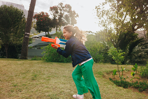 Child enjoying outdoor water gun play on a warm sunny day
