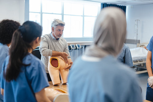 Doctor lecturing students on buttocks injection using a medical manikin